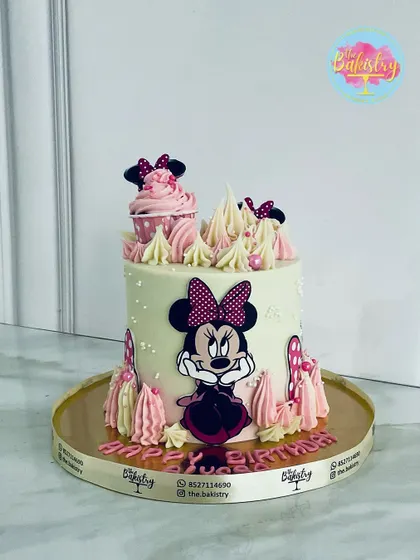 A sweet and stylish Minnie Mouse cake, featuring her iconic bow and polka dots, with pretty pink and white piping.