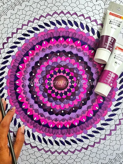 A work-in-progress shot of the magenta mandala. You can see the central part colored in, with the intricate line work of the outer layers still waiting for paint.
