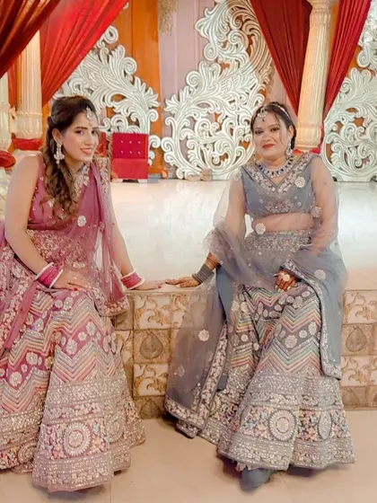 Two friends looking beautiful in their rented pastel lehengas. One is in a pink and silver piece, and the other in a grey floral one.