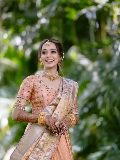 Bathed in blessings and glowing with happiness. This bride is radiant in her peach-toned South Indian outfit, with soft, luminous makeup and a beautiful, happy smile.