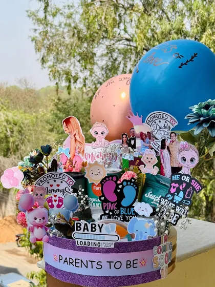 This "Parents to be" hamper is a celebration in a box, perfect for a baby shower or gender reveal. It’s personalized with the couple's photos and filled with snacks and cute baby-themed cutouts.