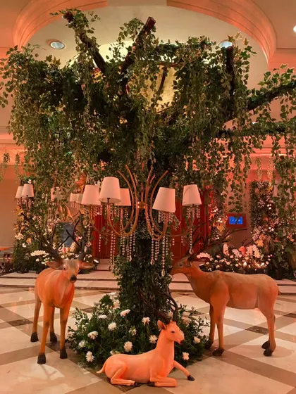 Life-sized deer figures gather around a tree in the enchanted forest theme, creating a magical, storybook scene at the entrance.