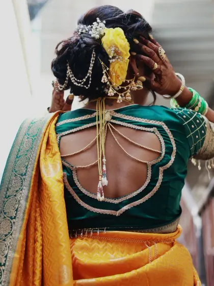 The back of the blouse and the hairstyle are key parts of the look. This photo shows a stylish blouse design and an intricate bun with floral and jewelry accents.