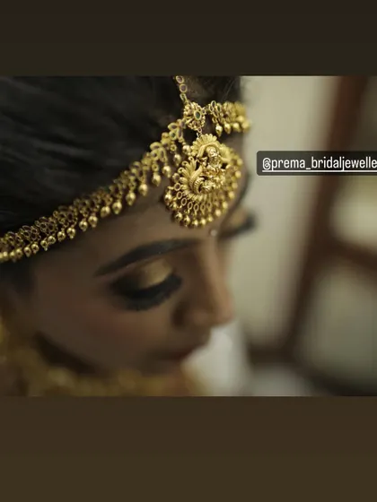 A close-up detail of a traditional temple maang tikka. This piece features a goddess motif and is an essential part of the South Indian bridal look.