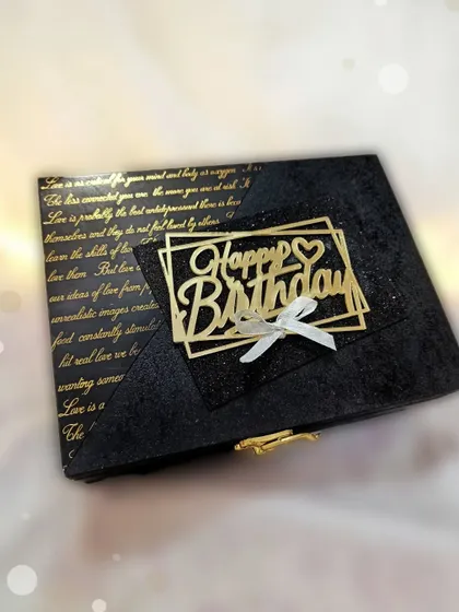A side view of the black vintage hamper box, showing the golden clasp and the intricate "Happy Birthday" topper.
