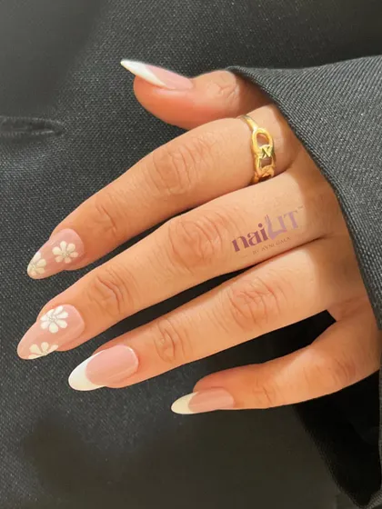 Another angle of the floral French nail extensions, showing how the delicate daisy art complements the clean, classic white tips.