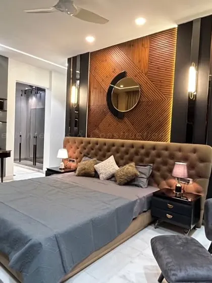A full view of the master bedroom, highlighting the multi-layered headboard wall that combines wood, textured panels, and ambient lighting. A dedicated study corner is seamlessly integrated into the design.
