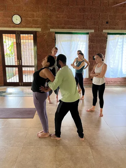 Our workshops create a space for committed students to improve their skills as teachers. Here, a group observes an adjustment for a standing backbend, learning through seeing and doing.