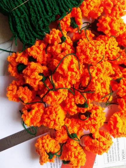 Getting ready for Navratri with a pile of handmade orange marigold flowers. This color represents the first day of the festival, and these blooms are perfect for the celebration.