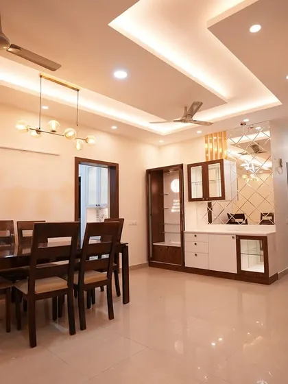 An elegant dining area designed for family gatherings. The modern chandelier, marble-finish wall accents, and custom crockery unit come together to create a sophisticated yet welcoming atmosphere.