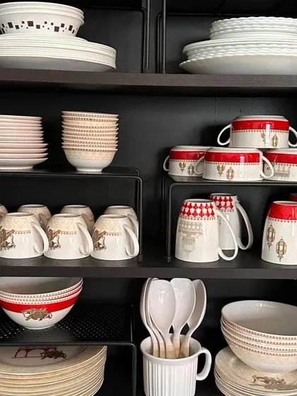 A beautifully organized crockery unit with a focus on space optimization and visibility. Shelf risers are key to achieving this clean and accessible setup.