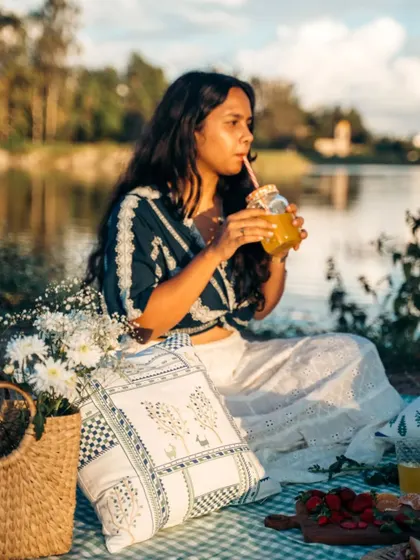 Enjoying a cool drink at a picnic, with our patchwork and floral cushion covers adding to the relaxed and stylish vibe.