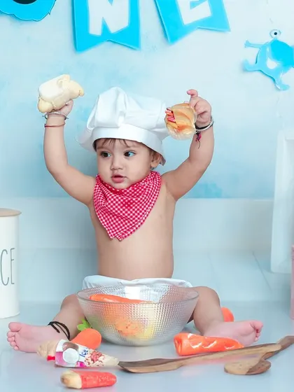 A triumphant moment in the kitchen. This little chef is proudly holding up his creations, ready to serve a meal of pure cuteness.