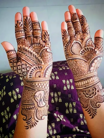 A lovely design featuring the initial 'K' inside a heart shape on the wrist, surrounded by a mix of traditional check and leaf patterns.