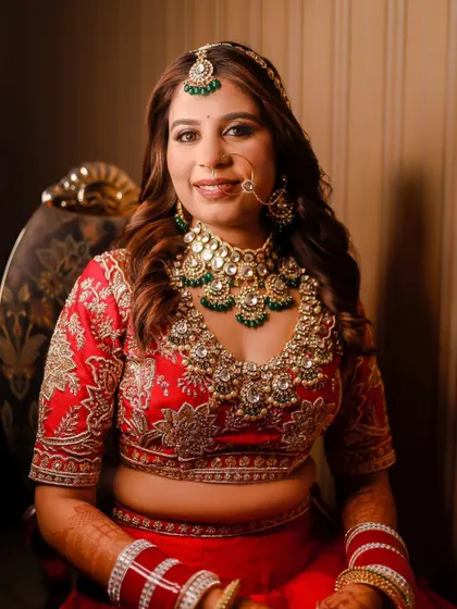 A classic seated bridal portrait, showcasing her radiant smile and the full splendor of her wedding attire and jewelry.
