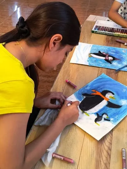 Another student in our penguin art class, adding details to her piece with soft pastels. This project is a favorite during our winter-themed sessions.