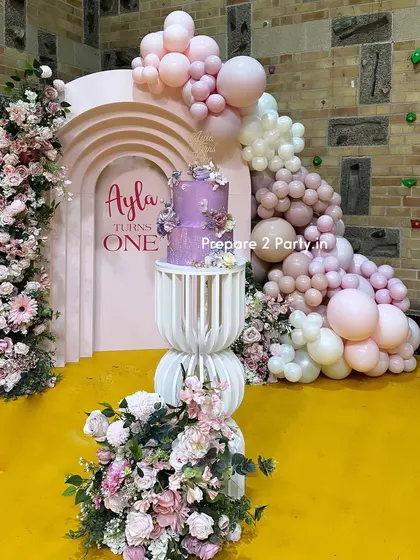 An elegant and artistic first birthday decoration. This setup features a 3D arched backdrop, beautiful floral towers, and a sophisticated balloon garland in muted pink tones, perfect for a chic celebration.