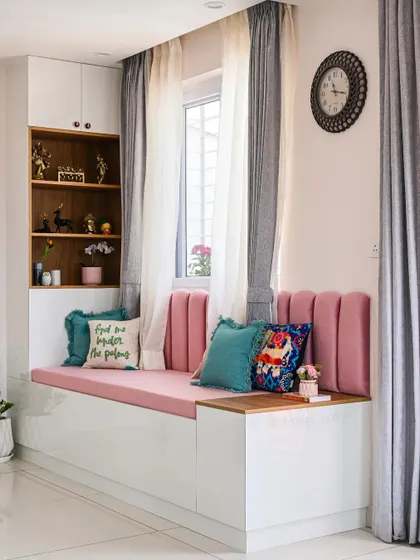A close-up of the cozy bay window seating area. With plush pink upholstery and decorative cushions, it’s the perfect spot to read a book or enjoy a cup of coffee.