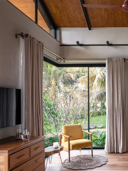 A cozy reading nook in a Grove House bedroom, positioned to catch the morning light and offer views of the garden. The high, pitched roof with exposed beams adds a sense of volume and character to the space.