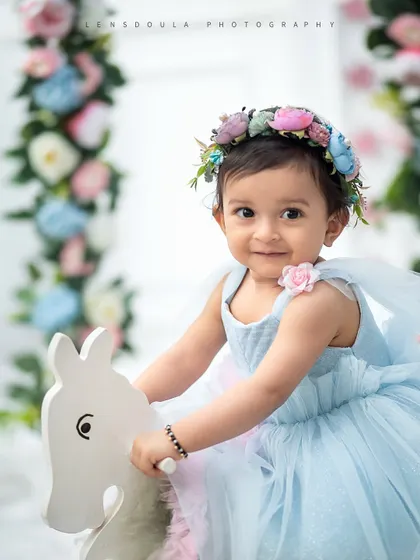 A close-up of our little flower fairy on her rocking horse, framed by a beautiful floral swing. The flower crown completes this enchanting look.