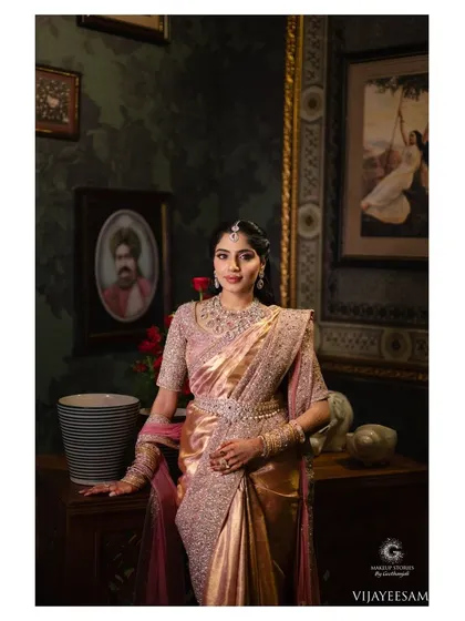 A full length portrait of Ashitha at her reception. The makeup is balanced and elegant, ensuring it works with the heavily embellished saree and diamond jewelry for a complete royal look.