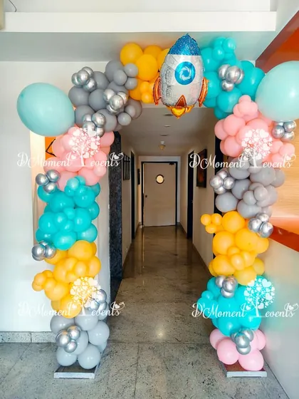 A space-themed balloon arch in bright colors with a rocket ship foil balloon, creating a fun entrance for an astronaut party.