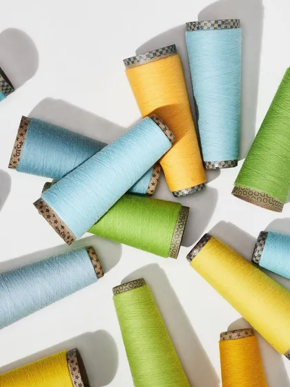 An overhead shot of scattered yarn cones in bright, cheerful colors. This playful composition is full of energy and highlights the vibrant potential of the raw materials.