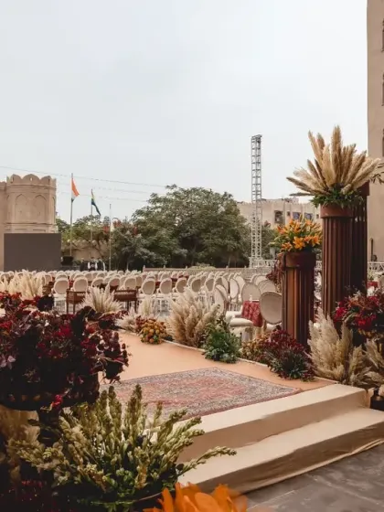 The aisle is lined with pillars topped with pampas grass and a mix of autumnal florals, creating a rustic yet regal pathway for the wedding procession.