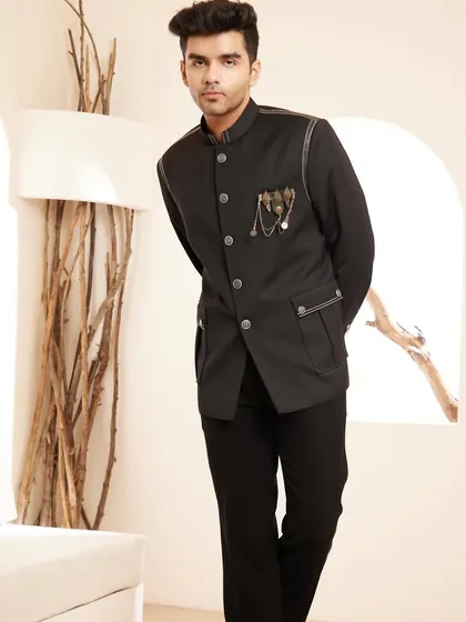 A modern interpretation of a timeless classic. This black bandhgala jacket features subtle leather piping and a distinctive metallic brooch, offering a sleek and sophisticated look for formal dinners and exclusive cocktail events.
