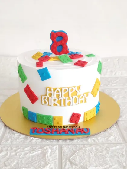 Building a fun 8th birthday with this Lego-themed cake. The design is covered in colorful, edible fondant bricks, making it a playful and delicious treat for a young builder.