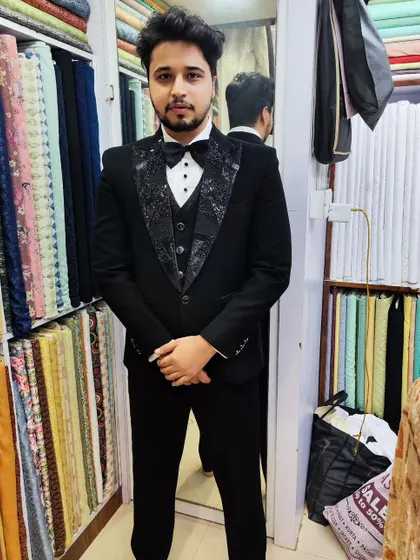 A full view of the client in his black tuxedo, featuring patterned, textured lapels that offer a modern twist on a classic garment.