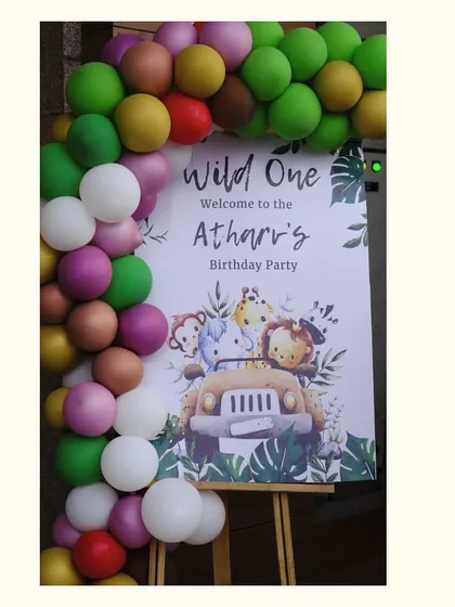 The welcome sign for Atharv's jungle party, framed by a balloon garland in a mix of bright and earthy tones.