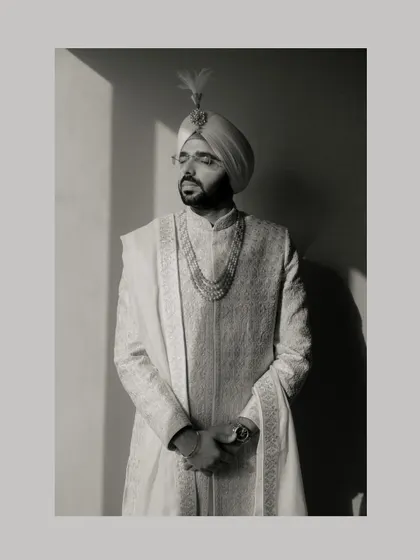 A classic and regal portrait of the groom in his sherwani and turban, using strong directional light to create a dramatic, high-contrast image.
