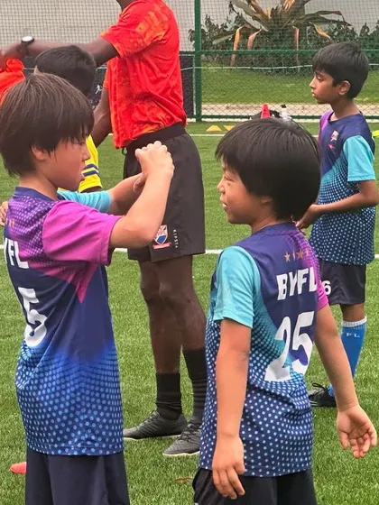 A coach and players interact during a drill. We use colorful equipment and positive reinforcement to make learning football skills an engaging and enjoyable experience for toddlers.