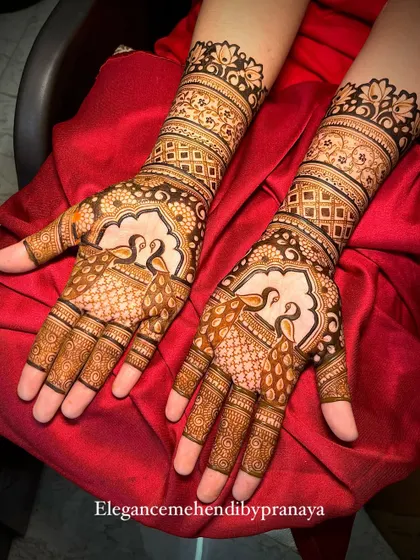 A classic engagement mehendi with graceful peacock figures on the palms. The design is filled with delicate netting and traditional patterns, extending up the forearms for a beautiful bridal feel.