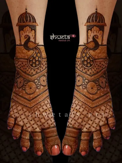 A beautiful peacock-themed leg mehendi design. The pattern features a large peacock under a dome, with intricate jaali work covering the rest of the foot for a traditional look.