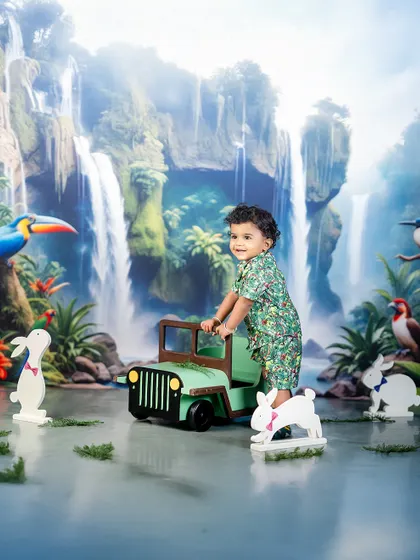 Lost in the forest and loving every minute of it! This jungle-themed shoot features a lush waterfall backdrop and a mini jeep for the little explorer.