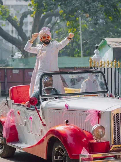 The groom's grand baraat entrance, dancing atop a vintage car.