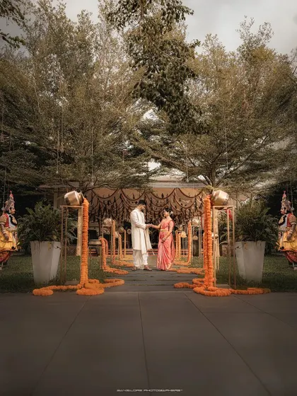 A wide, atmospheric shot of the wedding venue. The grand setup with marigold pathways and traditional performers creates a stunning visual for the ceremony.