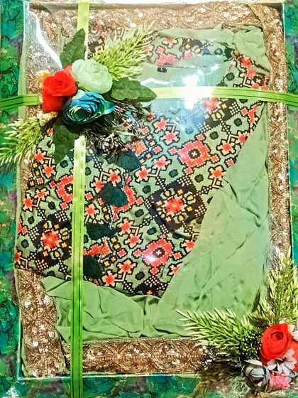 A green printed suit packed in a sequined tray with simple floral touches.