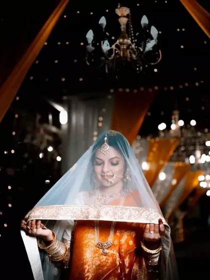 A stunning bridal portrait under a veil, with chandeliers and fairy lights creating a magical, glowing background.