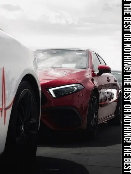 A dynamic shot of a red Mercedes-AMG, partially obscured by another vehicle, creating a sense of anticipation and focusing on its aggressive front design. This image captures the brand's motto: "The best or nothing."