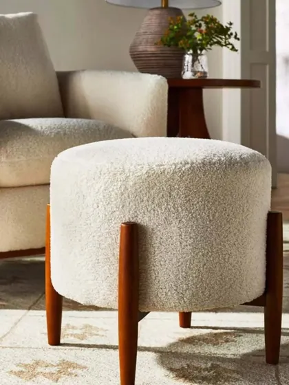 This comfortable pouf with solid wood legs is a versatile piece. It can be used as a footrest, extra seating, or even a small side table.
