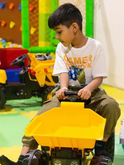 This young construction enthusiast is having a blast on the ride-on dumper truck, a popular choice for imaginative play.