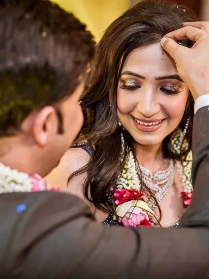 A serene moment of blessing. The bride closes her eyes as the groom performs a ritual, her face calm and full of emotion.