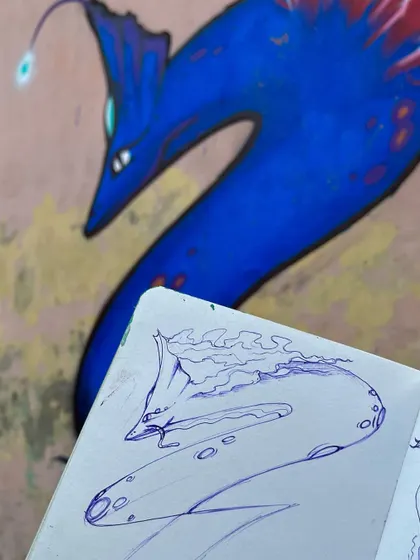 From my sketchbook to the wall. This image shows the initial pen sketch next to the final painted sea monster character.