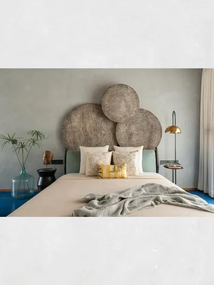 A close-up of the custom headboard in the Kamala Residence master suite, which is composed of three large, circular, distressed wooden panels.