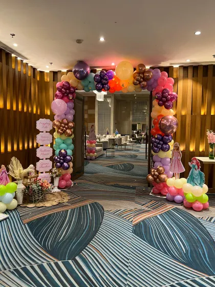 A colorful balloon arch at the entrance of a princess party, with cutouts of different Disney princesses welcoming the guests.
