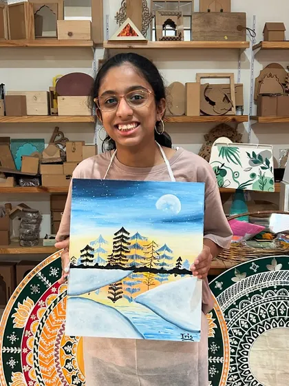 A smiling artist with her finished misty pine tree painting. This landscape workshop is a great way to connect with nature and create a beautiful piece of art for your home.
