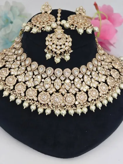 A beautiful champagne-gold Polki set with pearl accents, including a choker, earrings, and maang tikka.